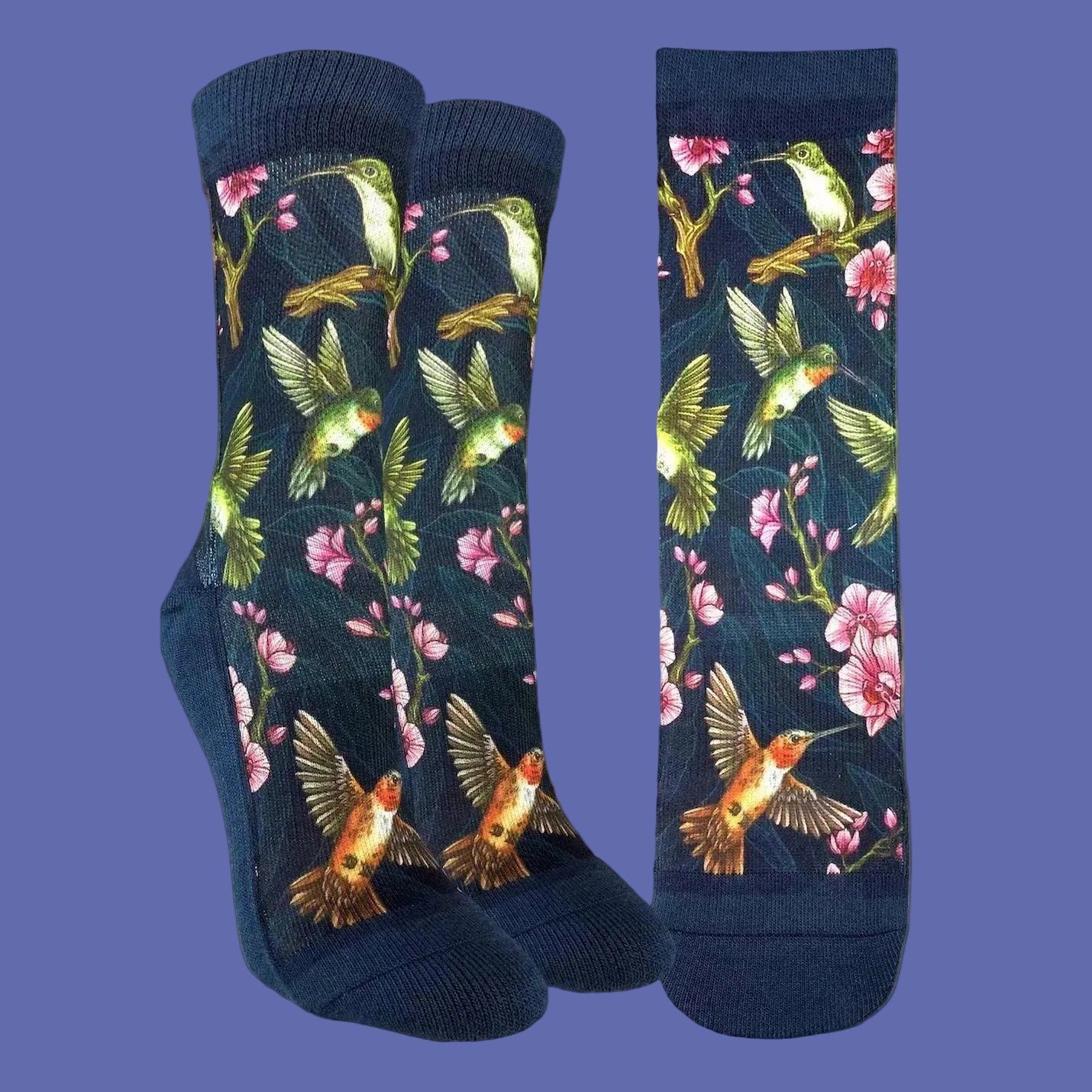 A pair of navy blue crew socks with a vibrant print of hummingbirds, pink blossoms, and green leaves, shown in both a folded view and a flat side view against a white background.