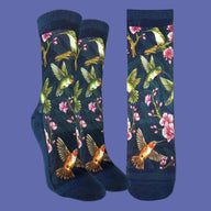 A pair of navy blue crew socks with a vibrant print of hummingbirds, pink blossoms, and green leaves, shown in both a folded view and a flat side view against a white background.