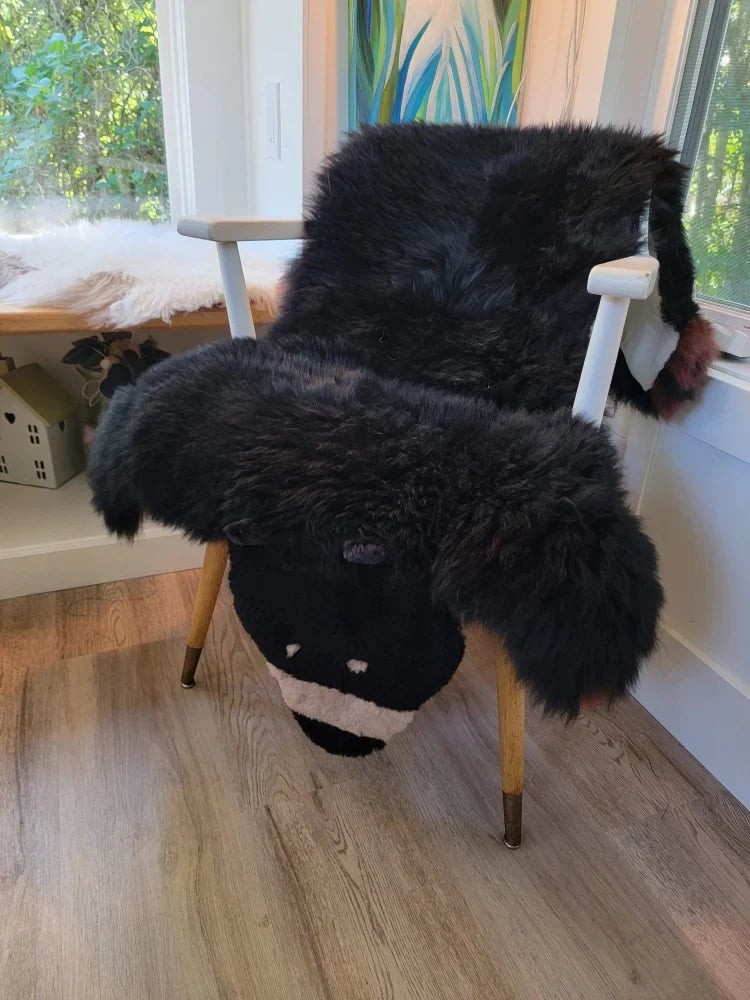 Adorable black bear rug shaped like a fluffy sheep chair cover made of soft merino sheepskin with wooden legs