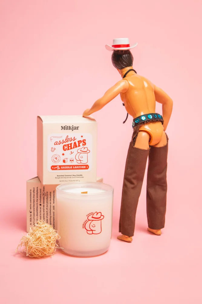 A white glass coconut soy candle with a red cowboy hat saddle leather design from milkjar assless chaps collection