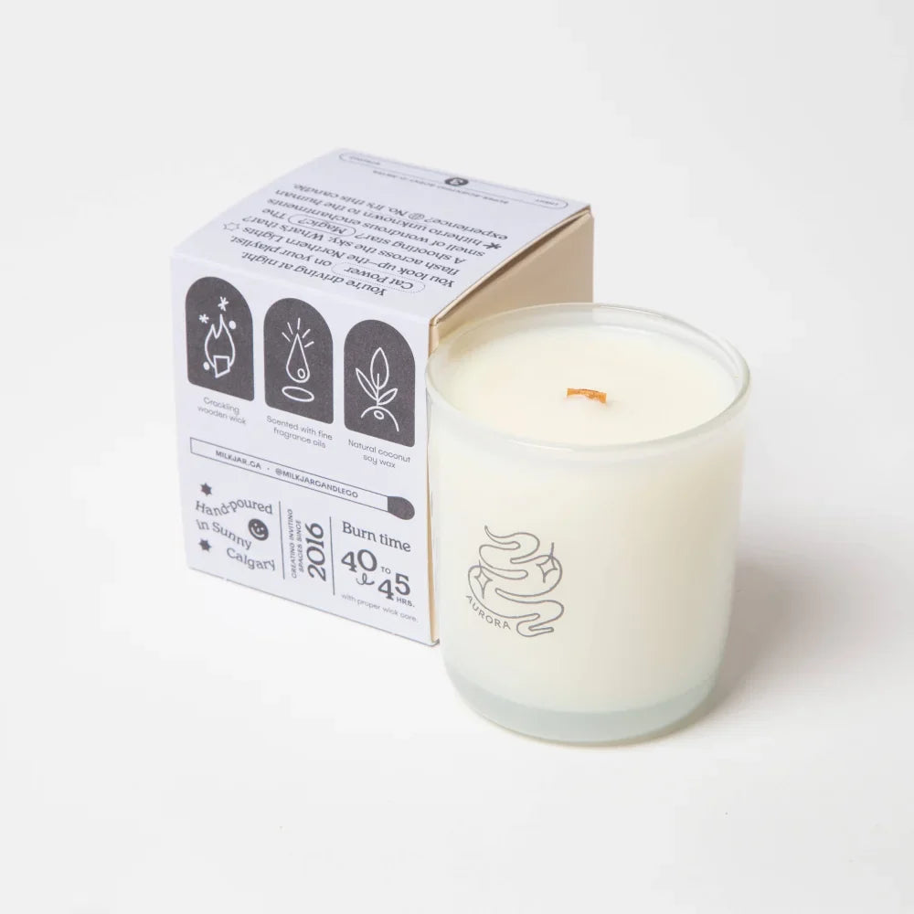 A white natural coconut soy wax candle in a clear glass jar with minimalist silver logo and branded packaging