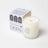 A white natural coconut soy wax candle in a clear glass jar with minimalist silver logo and branded packaging
