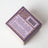 Backside of before sunrise milk and honey coconut soy candle box with purple gold speckles and safety instructions