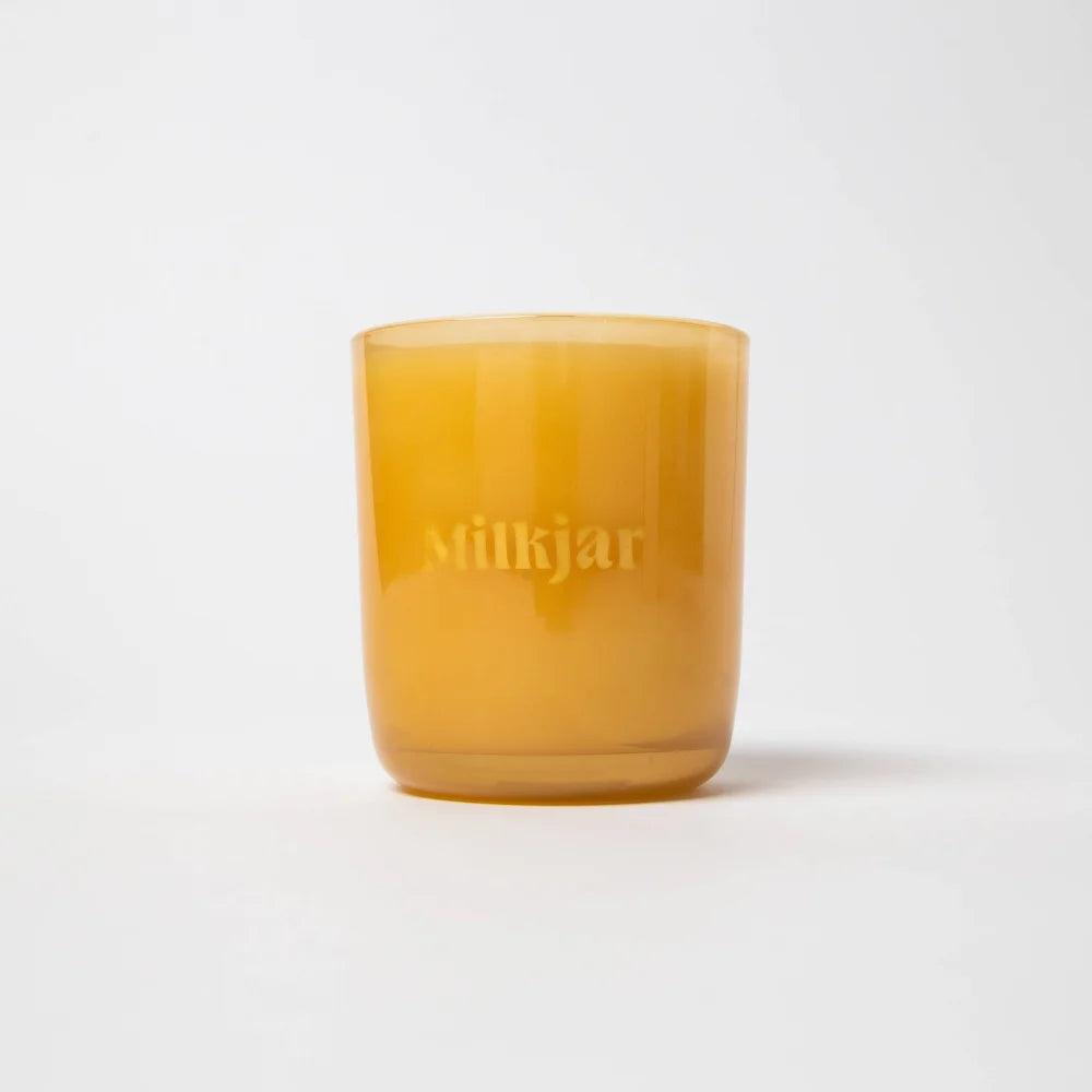 A translucent amber glass coconut soy candle jar from milkjar branded before sunrise milk and honey scent