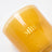 A translucent amber glass coconut soy candle jar with milkjar logo in gold lettering for cozy vibes like angus oliver rugs