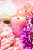 A pink essential oil coconut soy candle with white floral design and bloom text by angus oliver lit wick
