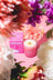 A pink milkjar essential oil coconut soy candle with white wax and gold wick by angus oliver among pastel flowers