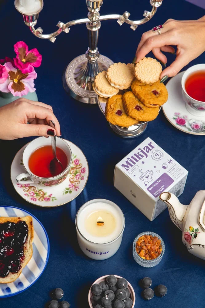 A white milkjar tea box with a purple label showing teapots and soy wax blueberry tea coconut soy candle