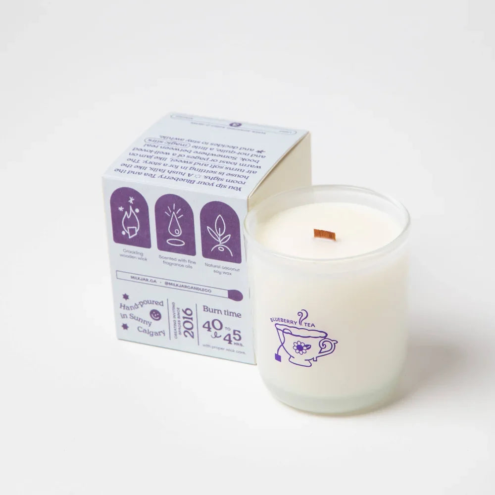 White blueberry tea scented coconut soy wax candle with wooden wick and purple teacup design in branded box