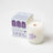 White blueberry tea scented coconut soy wax candle with wooden wick and purple teacup design in branded box
