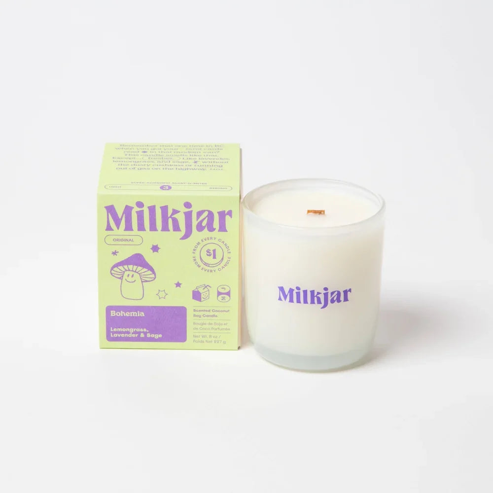 A white bohemia scented candle in a clear glass jar with purple branding and wooden wick made of coconut soy wax