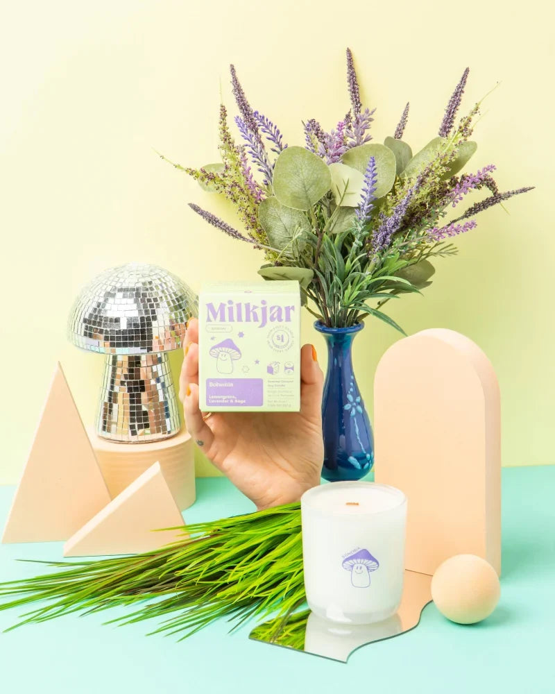 A white bohemia candle with purple mushroom design in a glass container made from coconut soy wax