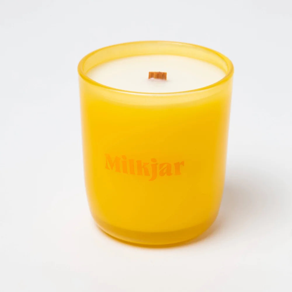 A vibrant yellow frosted glass citrus essential oil candle jar with wooden wick made from coconut soy by milkjar