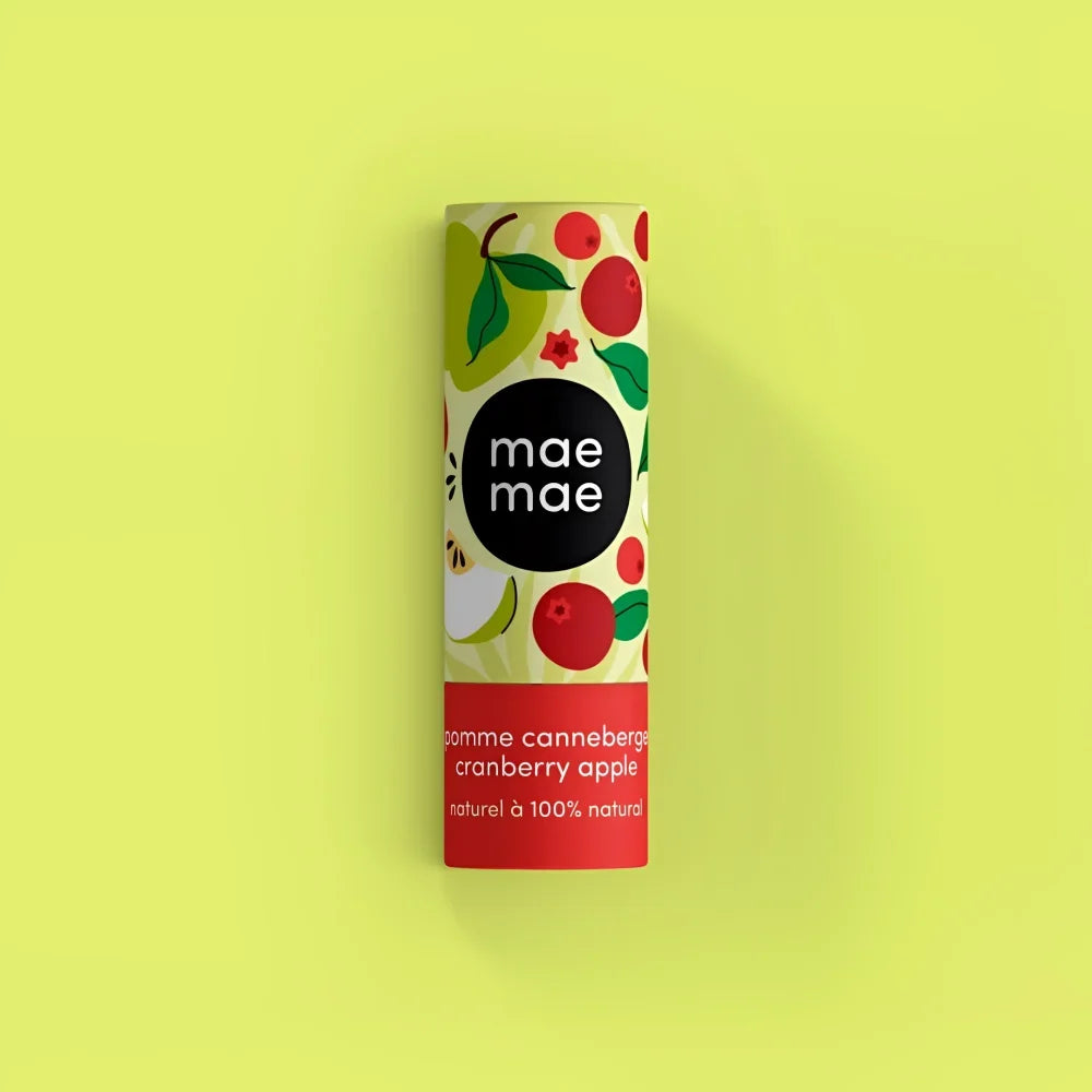 A cylindrical tube of mae mae cranberry apple natural lip balm with vibrant fruit design and bold red band for moisturizing lips