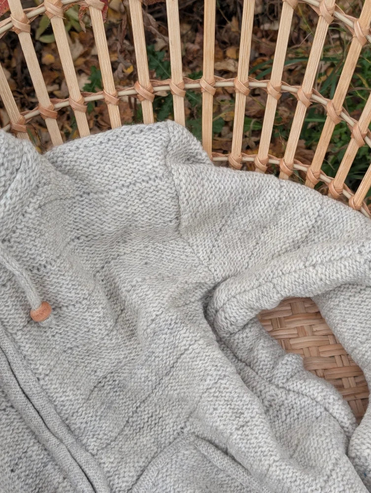 A soft fleece cream woolen calgary cardigan with light gray knit texture and wooden toggle closure