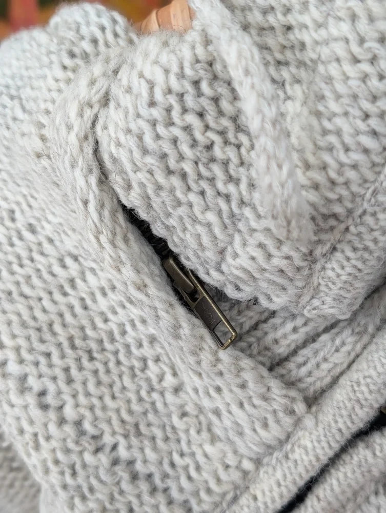 Close-up of cream woolen calgary cardigan with light gray chunky-knit zealand wool and soft fleece zipper pull detail