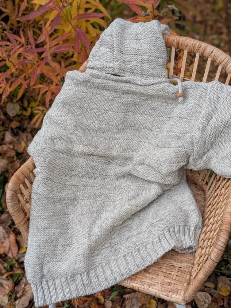 A cozy cream woolen calgary cardigan with soft fleece lining and a light gray knitted cowl neck and drawstring closure