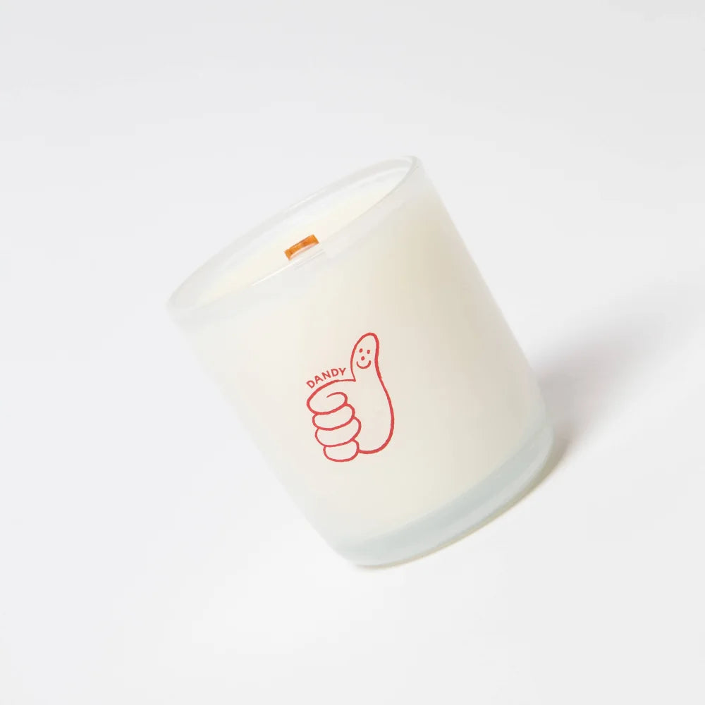 A white frosted glass coconut soy candle with a red thumbs up and dandy label by angus oliver