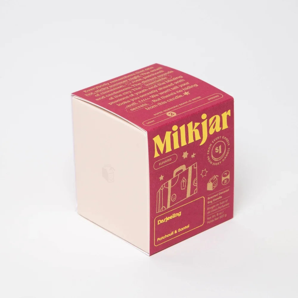 Darjeeling patchouli and santal coconut soy candle box in red and cream with gold lettering and suitcase graphic