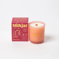 A peach-colored darjeeling patchouli and santal coconut soy candle in a frosted glass jar with wooden wick and gold lettering
