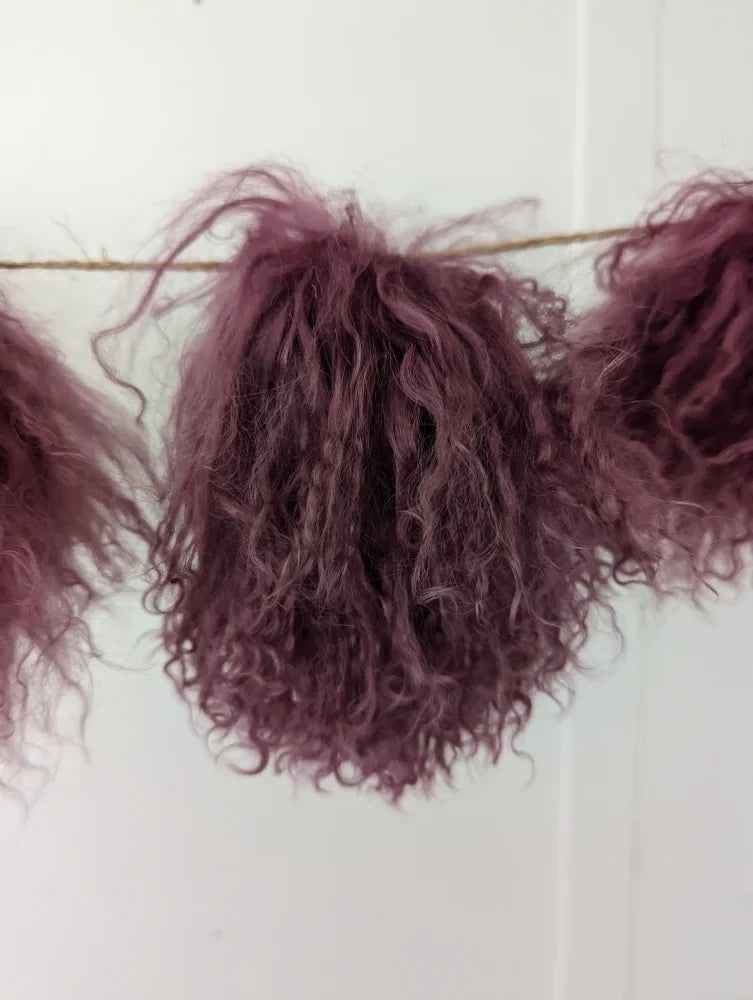 Dark pink sheepskin pom poms with maroon curly hair extension