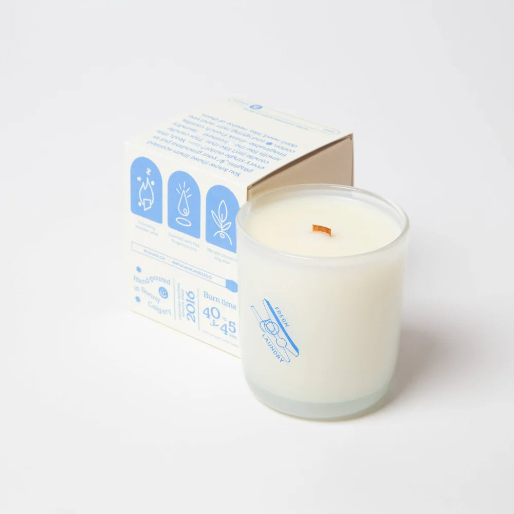A white fresh laundry scented coconut soy candle with wooden wick in clear glass jar and matching angus oliver box