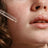 Clear glass dropper with rounded tip holding transparent glow & firm oil serum with seed oil and kernel oil