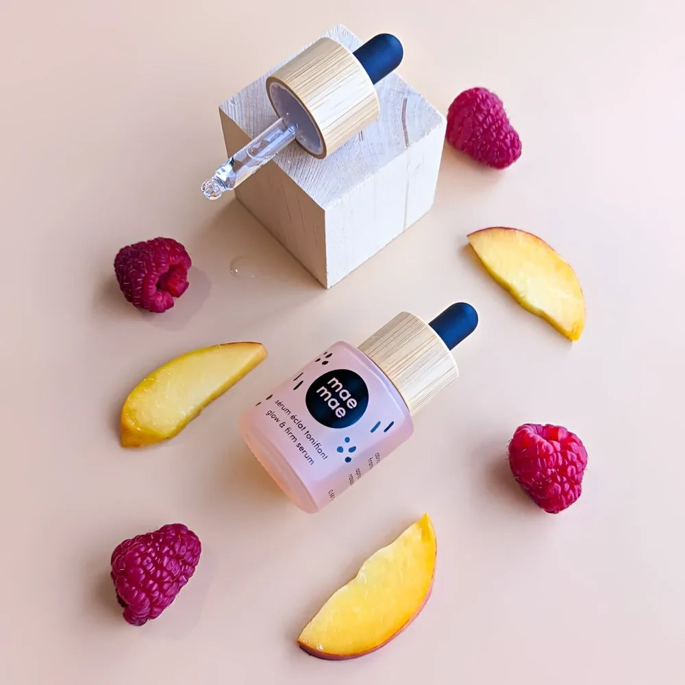 Pink glass dropper bottle with bamboo cap and blue bulb labeled mae mae glow and firm serum featuring seed and kernel oil