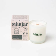 A frosted glass milkjar candle with white coconut soy wax and wooden wick labeled golden hour cashmere cedarwood coconut soy