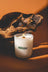 A white golden hour cashmere cedarwood coconut soy candle in clear glass jar with lit wooden wick and soy wax