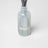 A translucent light gray glass reed diffuser bottle with white milkjar logo for golden hour scent blend