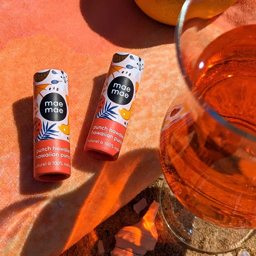Two cylindrical hawaiian punch zinc lip balms with colorful tropical packaging featuring nano zinc oxide and fruit designs