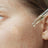 Clear glass dropper with a drop of hydrate and purify oil serum containing strawberry seed oil above skin