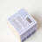 Back of white speckled cardboard box with barcode and safety info for hygge vanilla tobacco cedar coconut soy candle