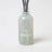 A frosted glass reed diffuser bottle with dark gray sticks and an etched teapot design labeled milkjar featuring sea salt scent