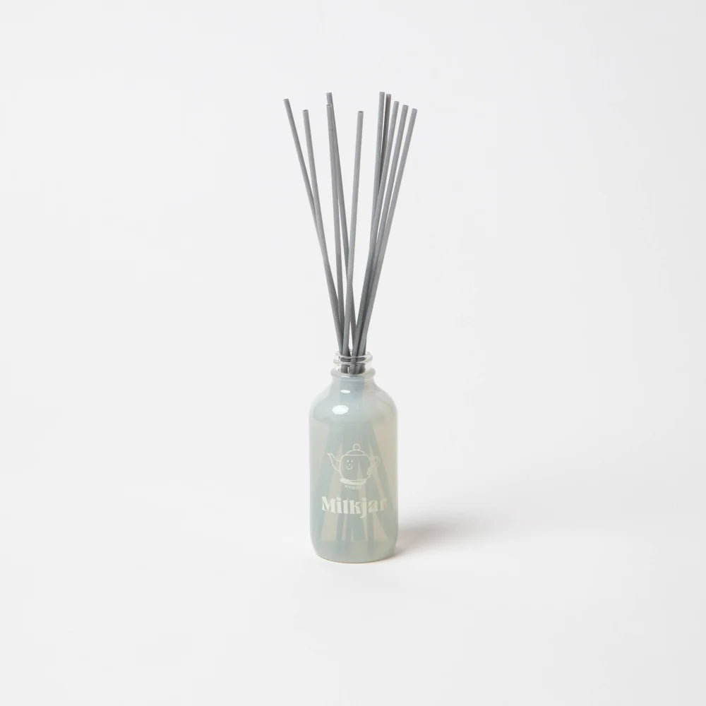 A sleek translucent light gray glass reed diffuser bottle with silver sticks for vanilla tobacco and sea salt scent