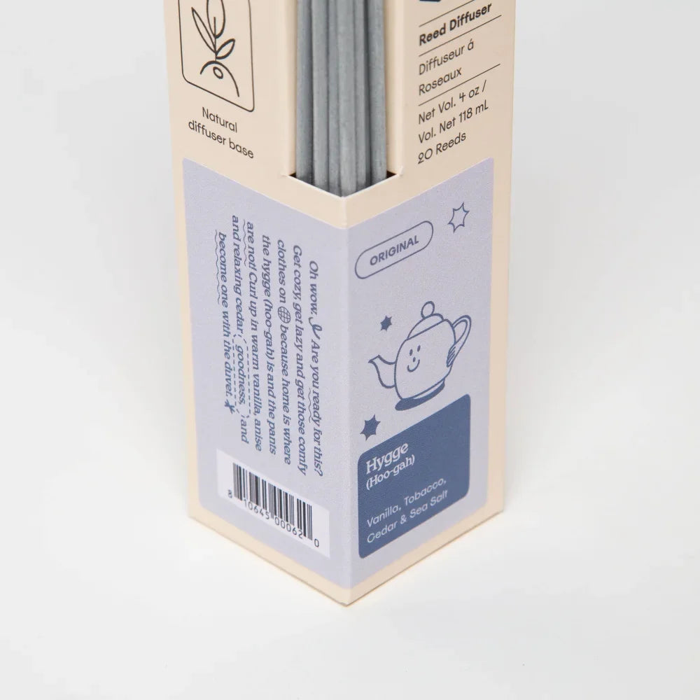 A beige cardboard box with 20 gray reed diffuser sticks labeled hygge with vanilla tobacco cedar and sea salt scents