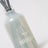 A translucent gray frosted glass reed diffuser bottle with etched teapot and milkja logo for sea salt scent
