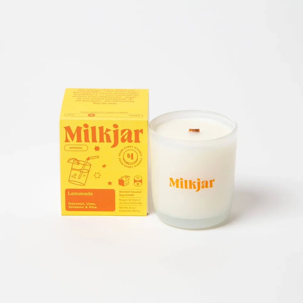 White milkjar lemonade scented coconut soy candle in clear glass jar with orange logo for fresh home vibes