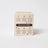Beige cardboard box with black text and dark brown banner showing candle care for lemonade coconut soy 8 oz candle back side