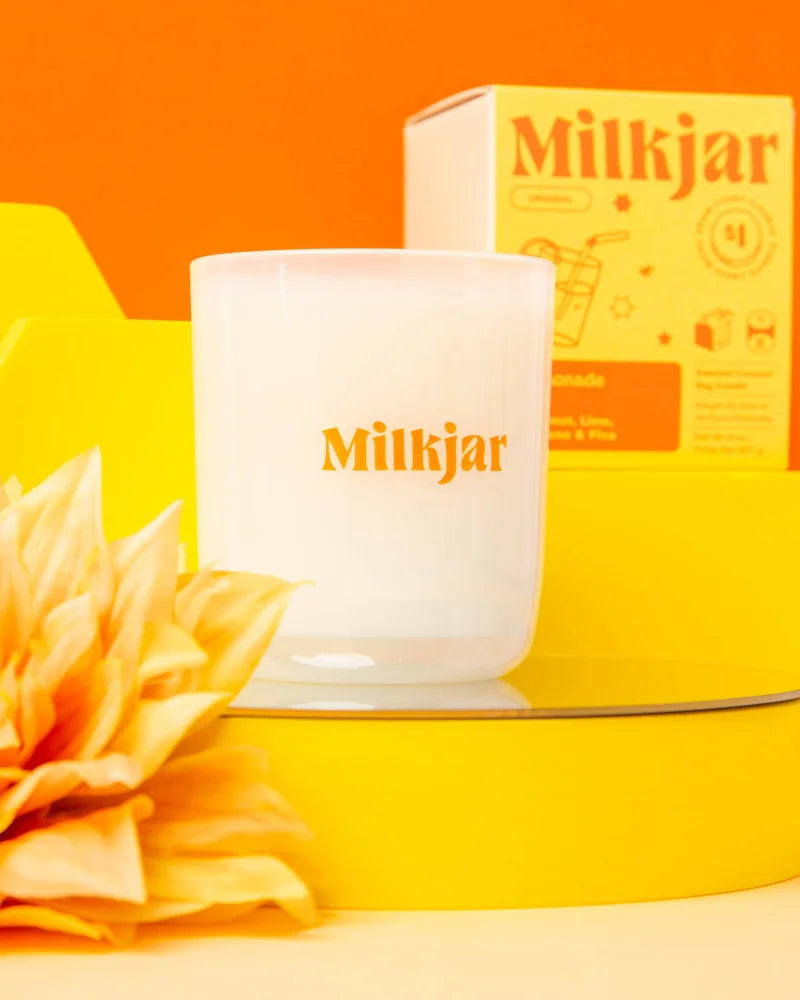 White milkjar coconut soy candle in frosted glass jar with orange lettering lemonade coconut lime pine scent