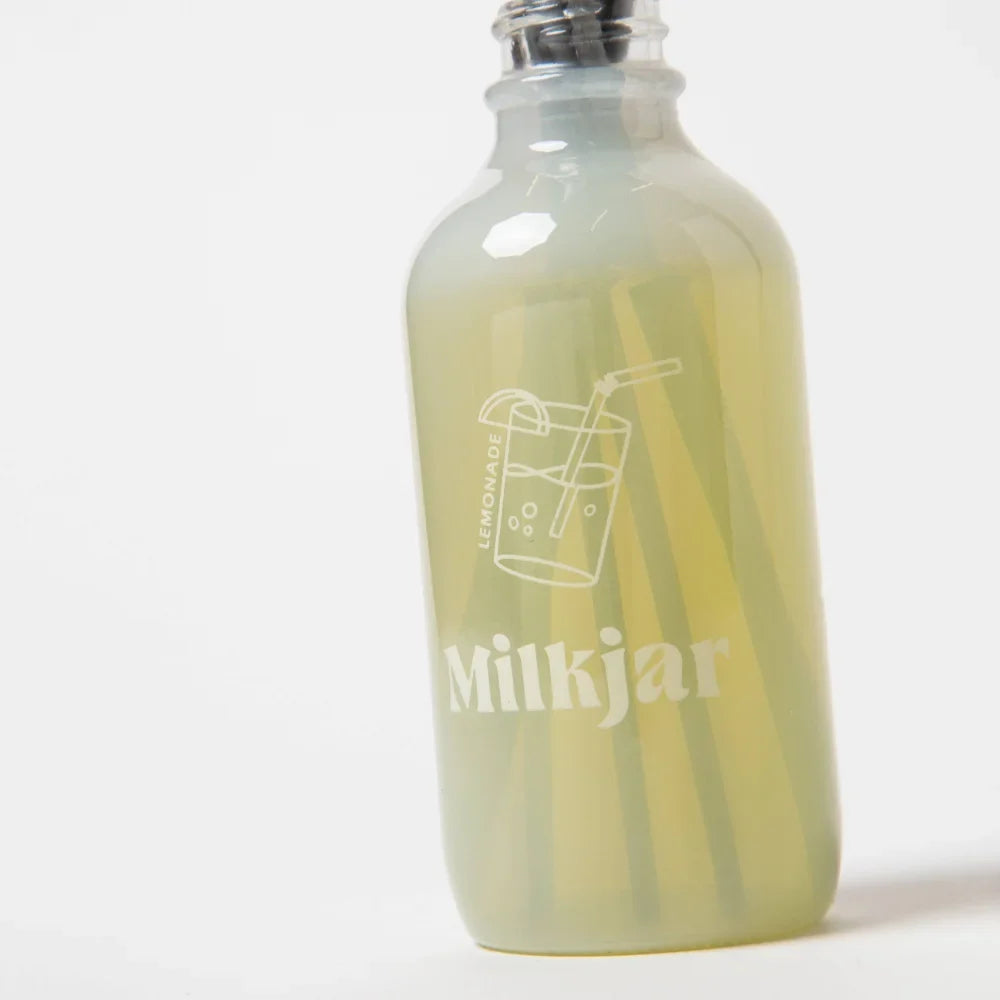 A translucent green glass reed diffuser bottle with silver cap and milkjar logo for lemonade coconut lime verbena pine