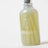 A translucent green glass reed diffuser bottle with silver cap and milkjar logo for lemonade coconut lime verbena pine