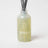A translucent pale green glass reed diffuser bottle with minimalist white logo and dark gray sticks lemonadelime verbena pine