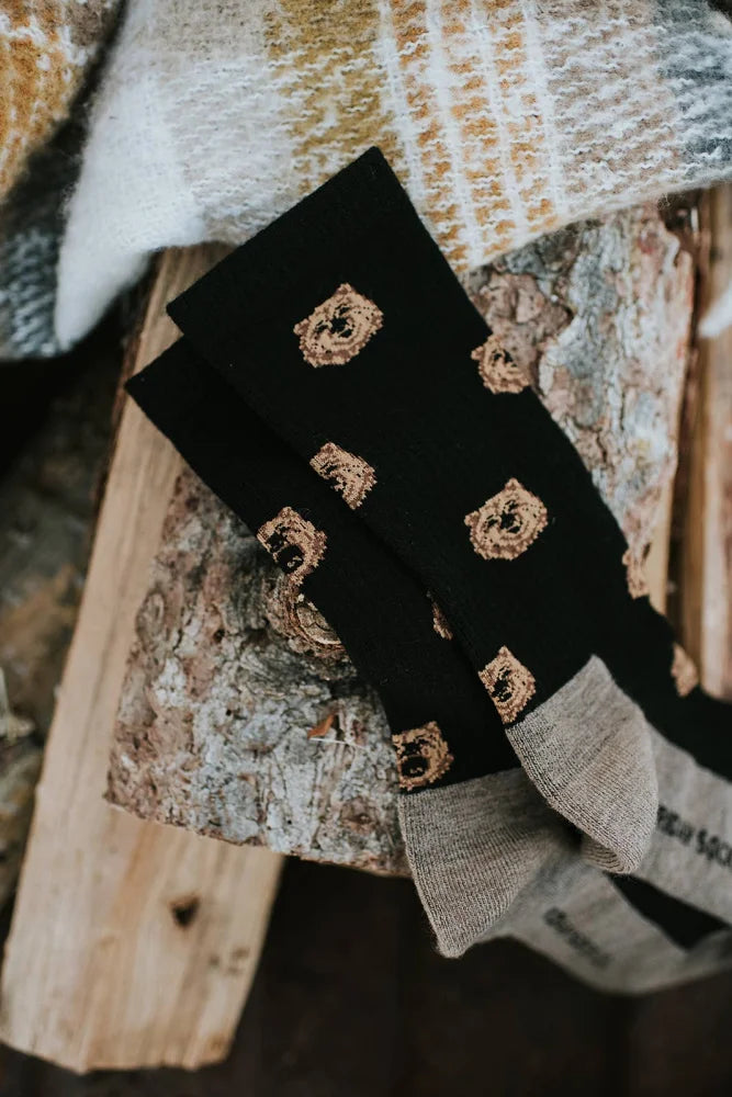 Men’s black merino wool socks with embroidered gold bear faces and gray ribbed cuffs for soft comfort