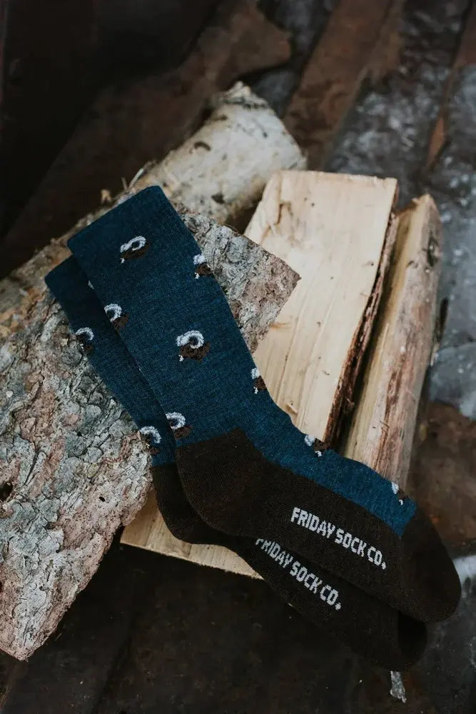 Dark teal merino wool socks with white and brown sheep pattern and friday sock co logo on the heel for hiking