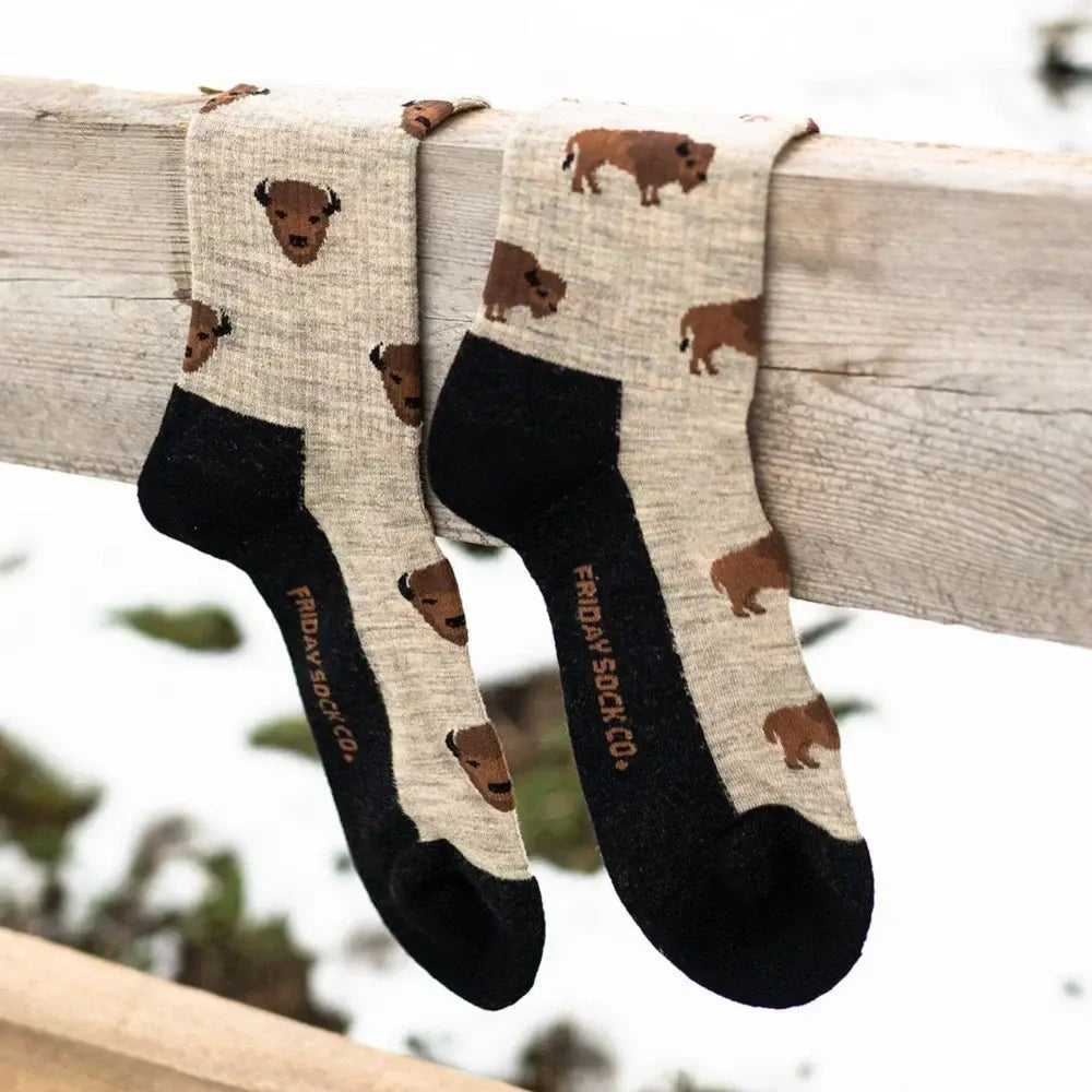 A pair of beige merino wool socks with brown bison prints black toe and heel by friday sock co for hiking