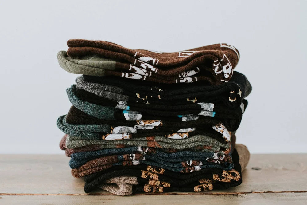A stack of men’s owl merino wool socks in earthy tones with whimsical animal designs warm breathable wool socks