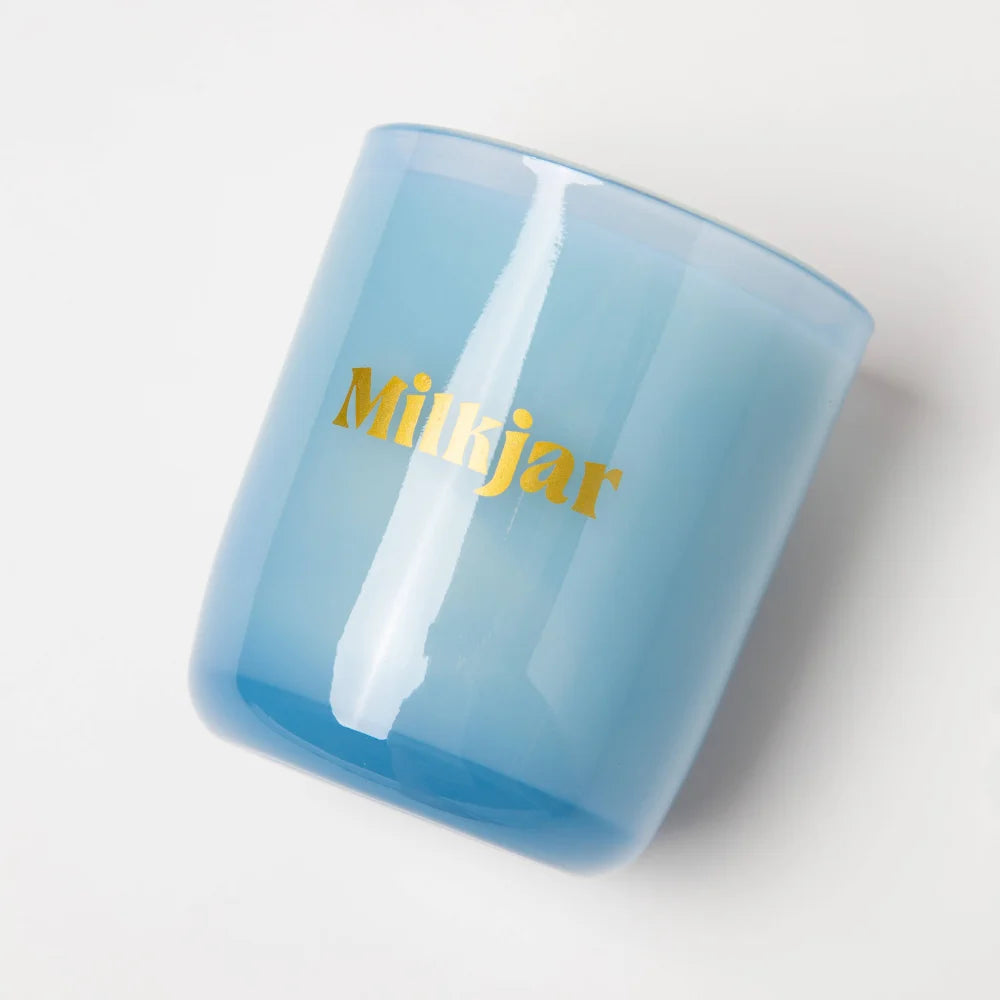 A translucent light blue glass jar candle with gold mikjar logo moonrise neroli plum coconut soy 8oz candle