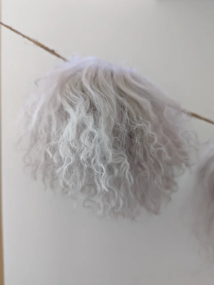 White curly mushroom sheepskin pom hanging from wooden stick